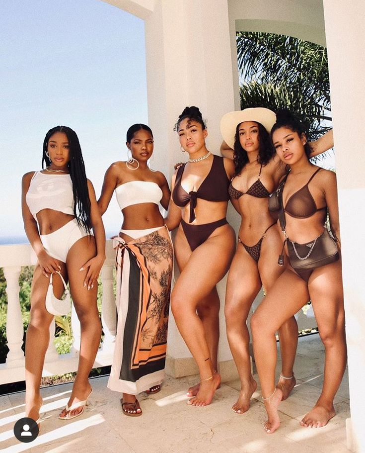 A group in swimwear and resort looks posing at a white villa