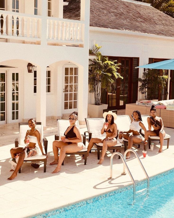 Women relaxing poolside at a white villa