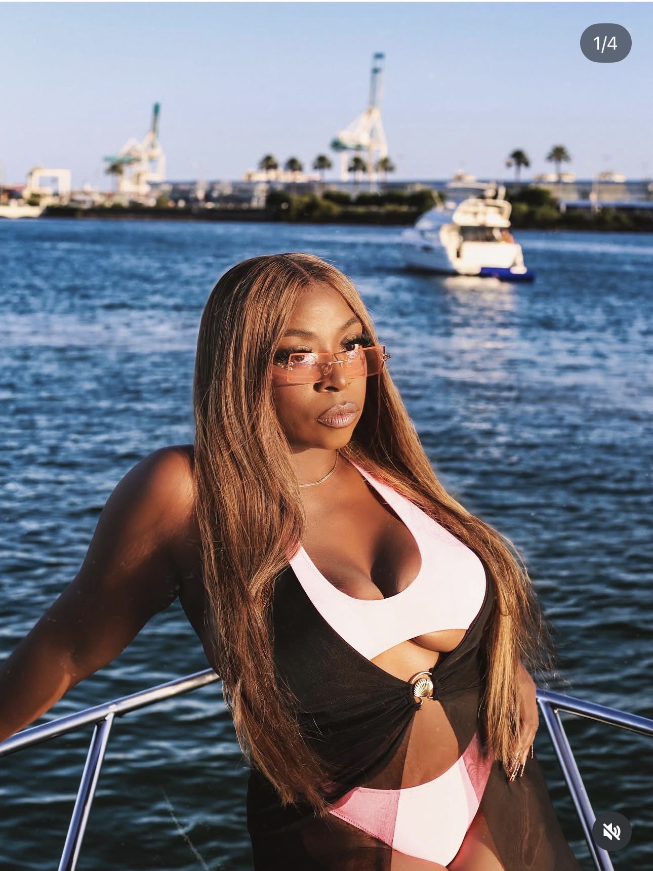 Keke Nova on a yacht in a black, pink, and white swimsuit